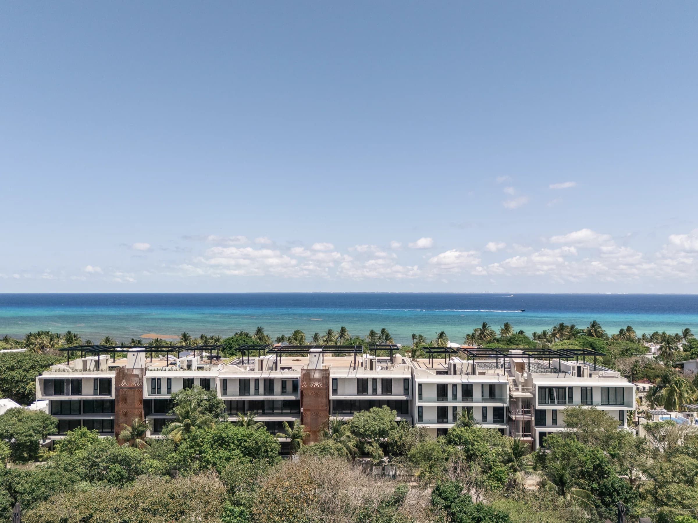 Los tres edificios de Soleii terminados entre la selva de Playacar, con el Mar Caribe al fondo